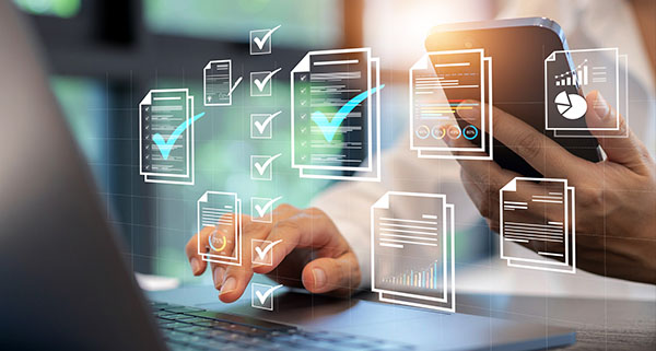 person working on laptop while using smartphone checking documents with digital graphs and statistics representing 10 tasks completed
